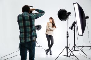 Photographer working with female model in equipped studio